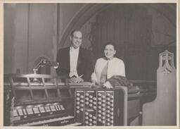 Man and woman posing for a photo behind the organ
