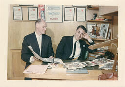 Syd Freedman sitting beside an unknown man at his desk