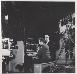 CBC cameras filming two men at the organ