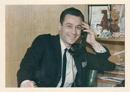 Syd Freedman at his desk holding a telephone