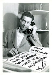 Syd Freedman at his desk in front of a cartoon book