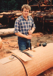 Man preparing cedar log at saw mill